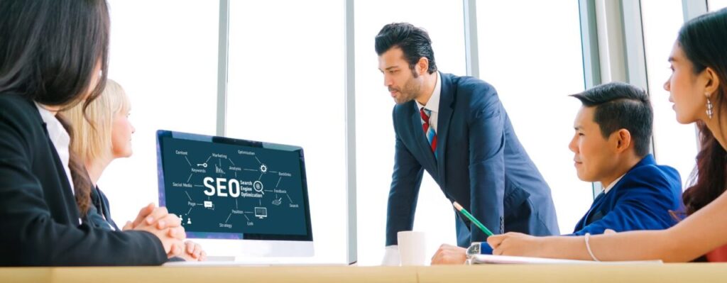 Équipe d’une agence SEO réunie autour d’un ordinateur pour définir une stratégie d’acquisition.
