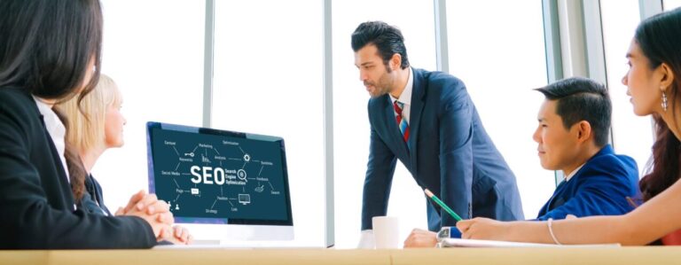 Équipe d’une agence SEO réunie autour d’un ordinateur pour définir une stratégie d’acquisition.